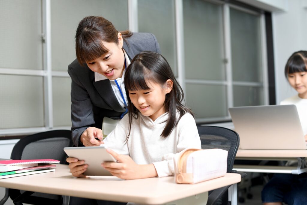タブレットを持った女の子に指導をしている女性教員