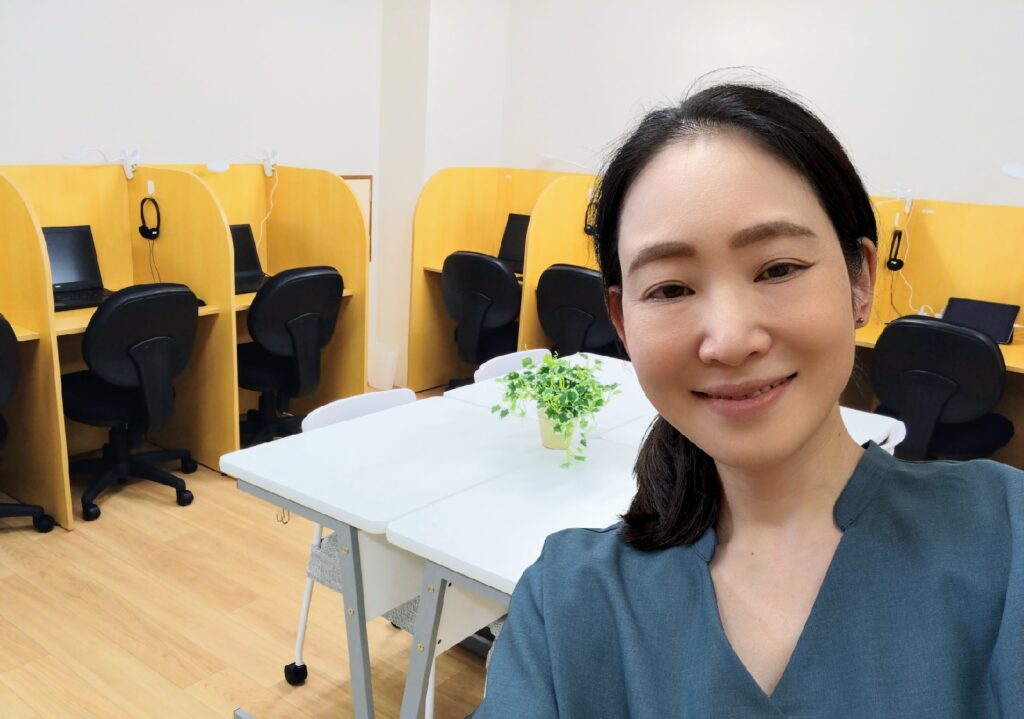 清潔な教室をバックに笑顔で写る女性教員